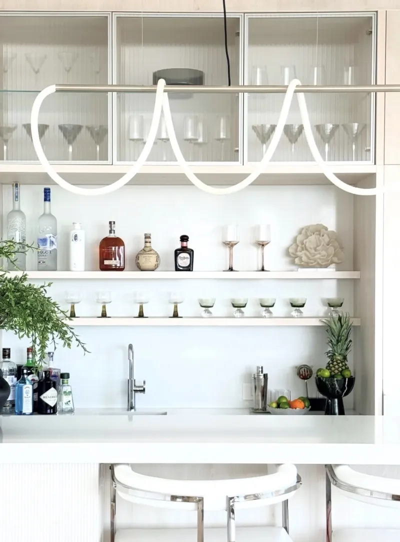 Bar with glassware, bottles, greenery, and sculptural lighting
