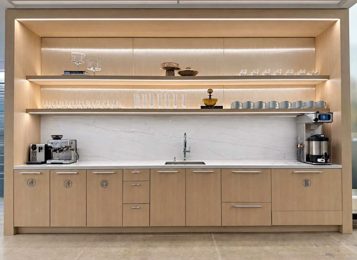 Corporate café bar in Manhattan with illuminated oak shelving, glassware, stoneware and amber vessels