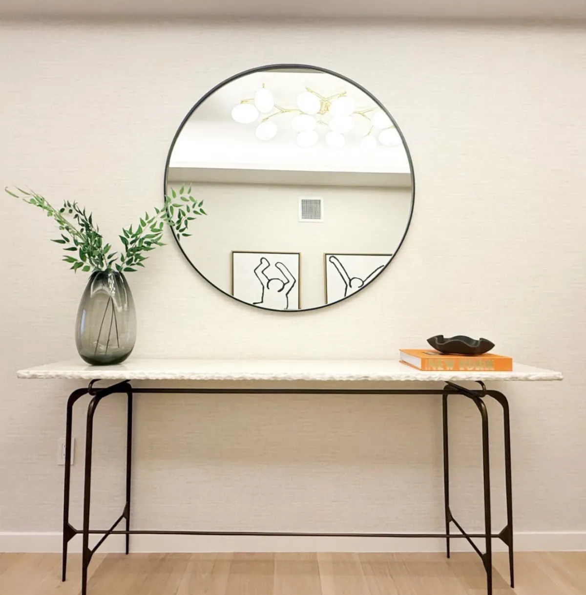 Entry console with a circular mirror, vase, and books