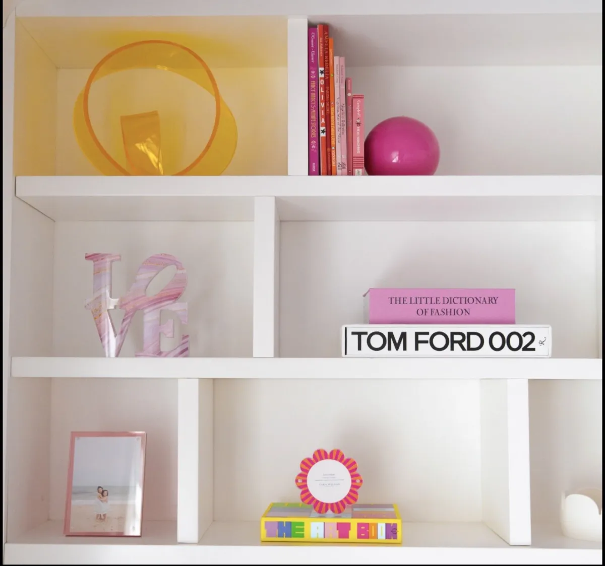 Colorful books and objects arranged on white shelves