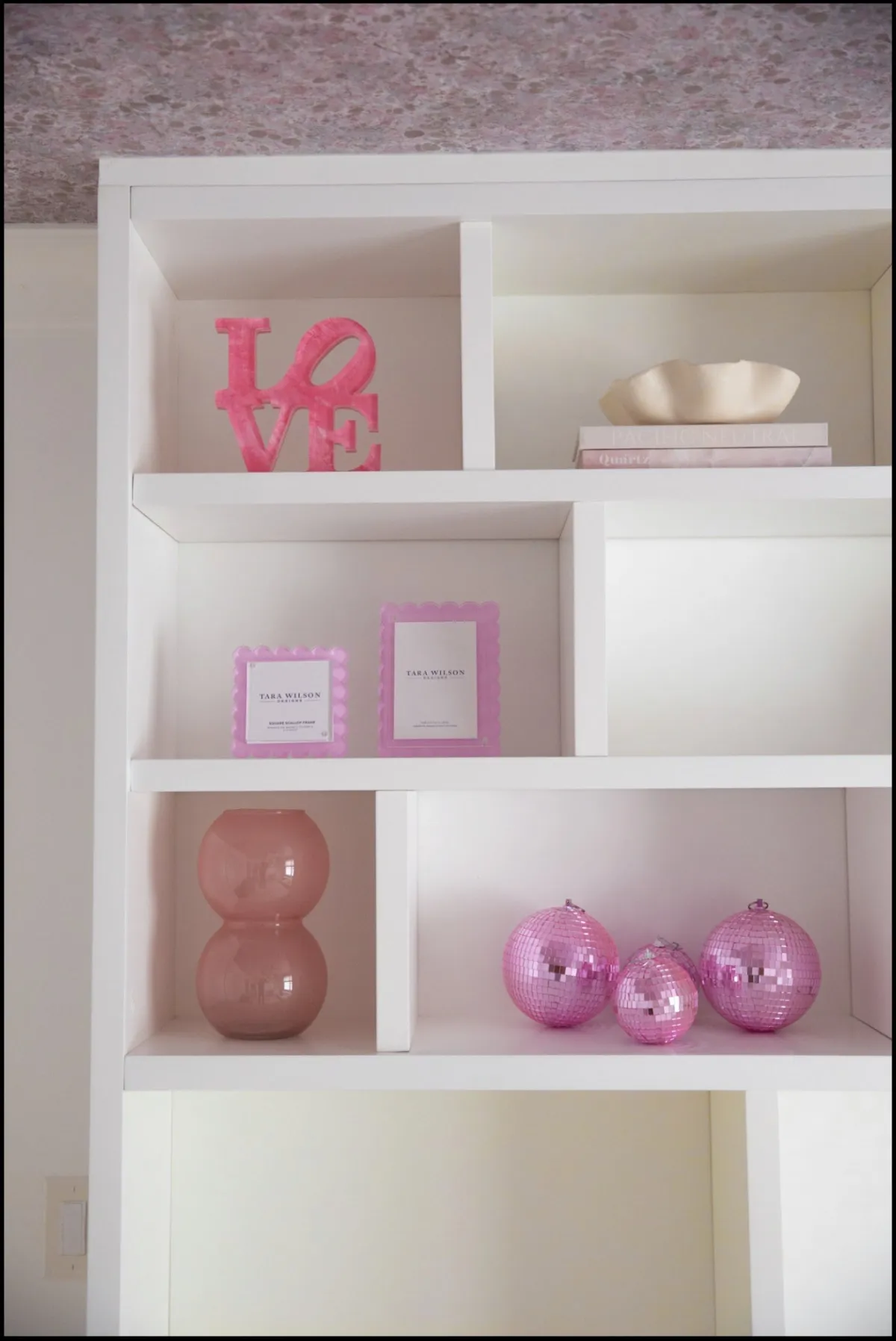 Pink sculptural objects on white built-in shelves