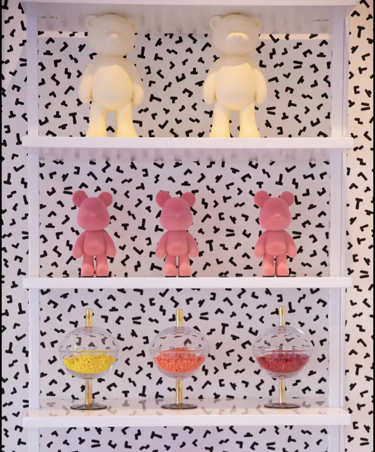 Pink figurines and colored glass on patterned shelving
