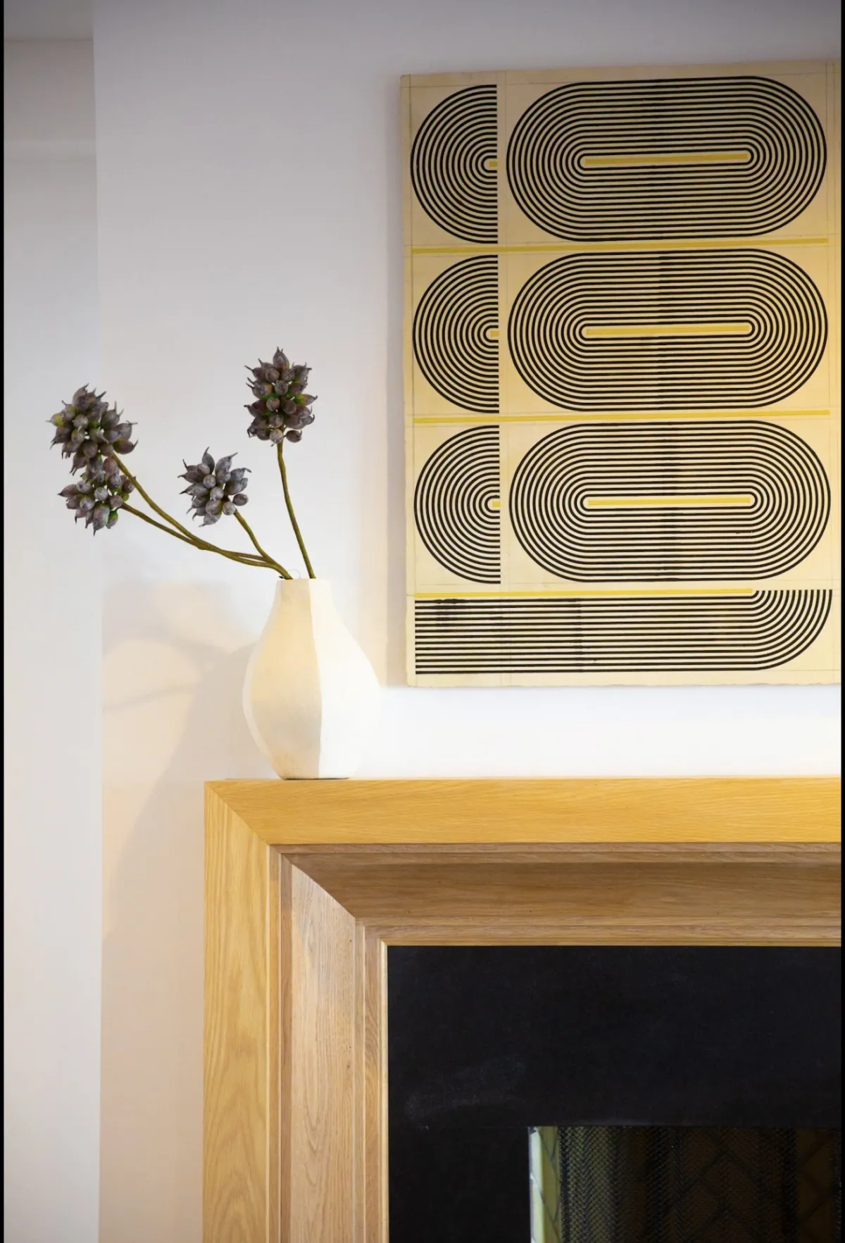 Detail of sculptural vase and graphic artwork above the fireplace