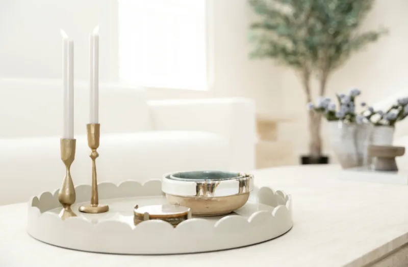 Brass candlesticks and ceramic bowl on a white scalloped tray
