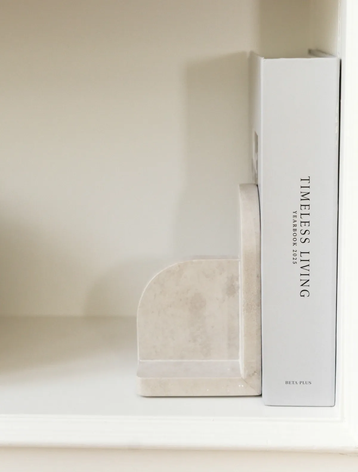 Sculptural bookend beside a design book on a white shelf
