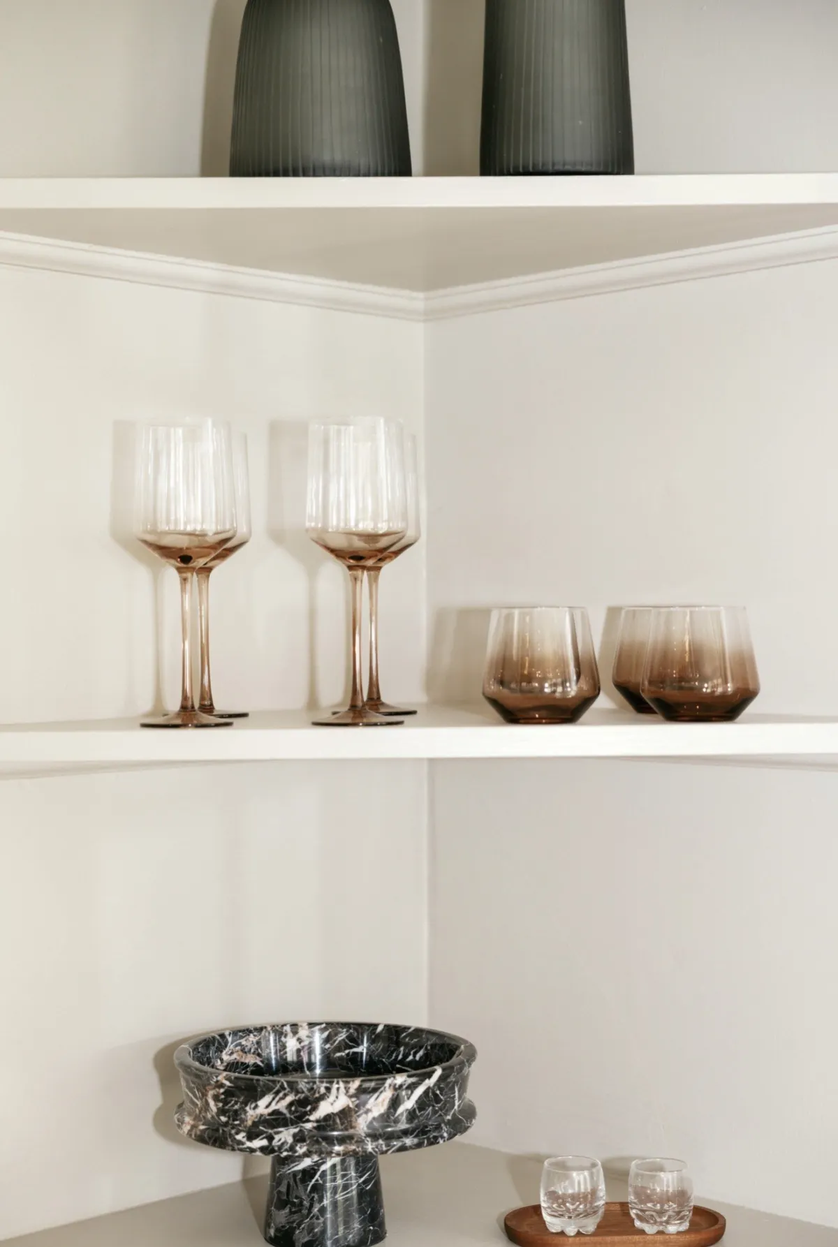 Rose glassware and black marble bowl on white bar shelves