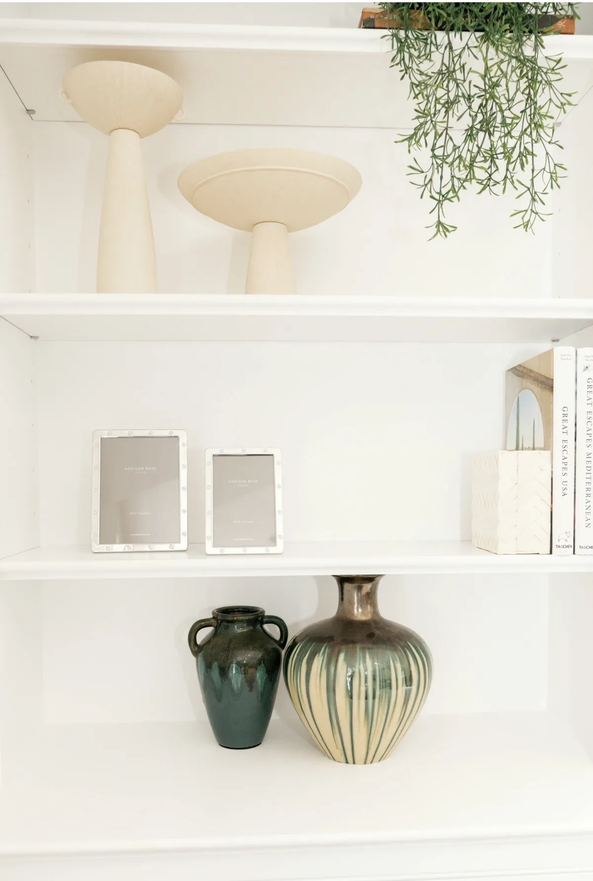 Neutral decor and green ceramics arranged on white built-in shelves