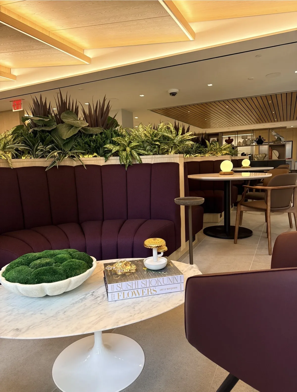 Workplace lounge with planter greenery, a moss bowl and books on a marble tulip table