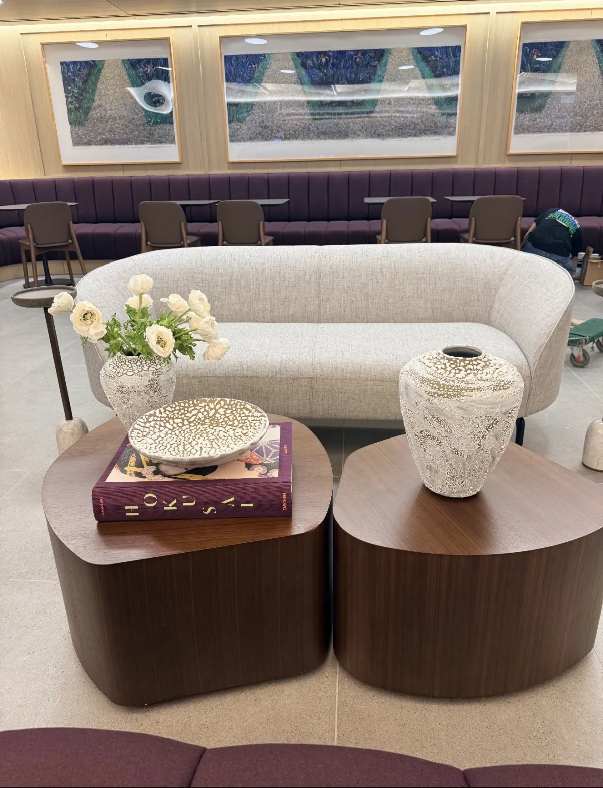 Curved sofa with walnut drum tables styled with a sculptural vase and art books