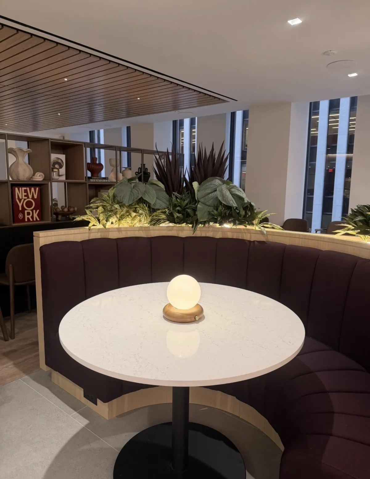 Café booth with a white table and a glowing globe lamp under a slatted wood ceiling