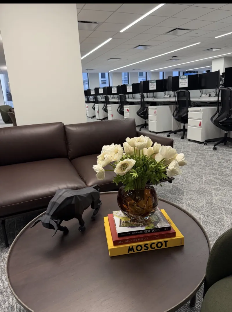 White anemones in an amber vase with a panther figurine, open office beyond