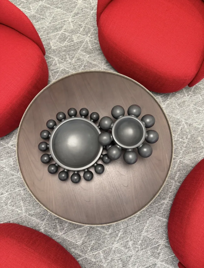 Overhead view of a walnut tray of silver spheres between red lounge chairs